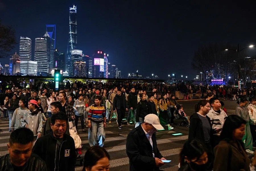 People cross a street on the Bund in Shanghai on 2 April 2026. (Hector Retamal/AFP)
