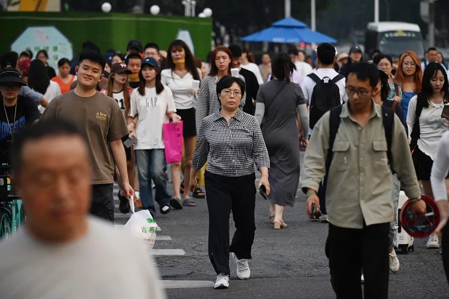 People cross an intersection during rush hour in Beijing, China, on 9 July 2024. (Greg Baker/AFP)