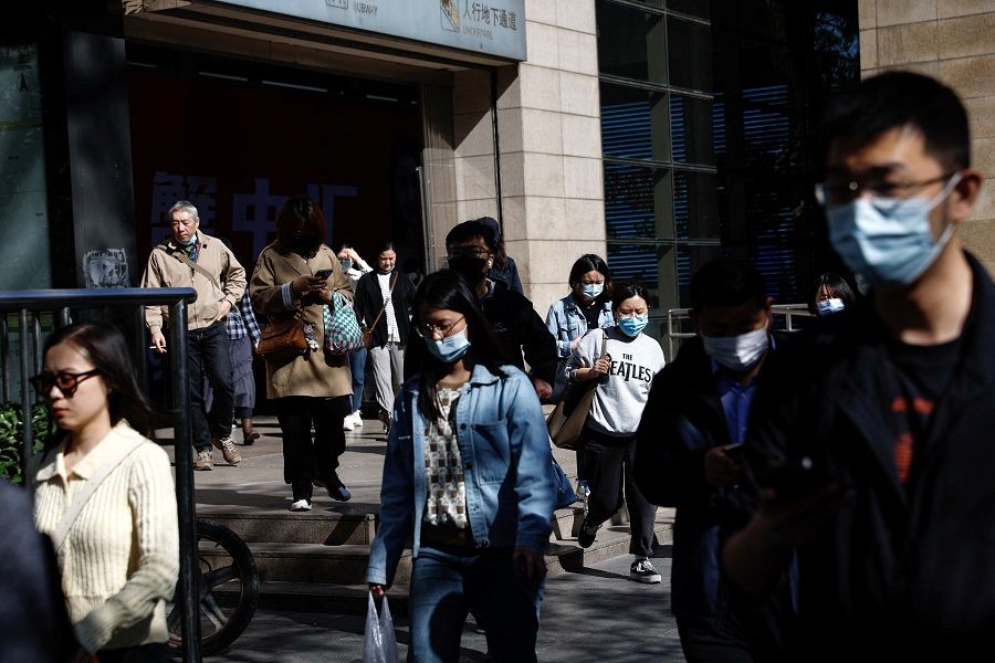 People walk out of a subway station during morning rush hour, in Beijing, China, 18 April 2023. (Tingshu Wang/Reuters)