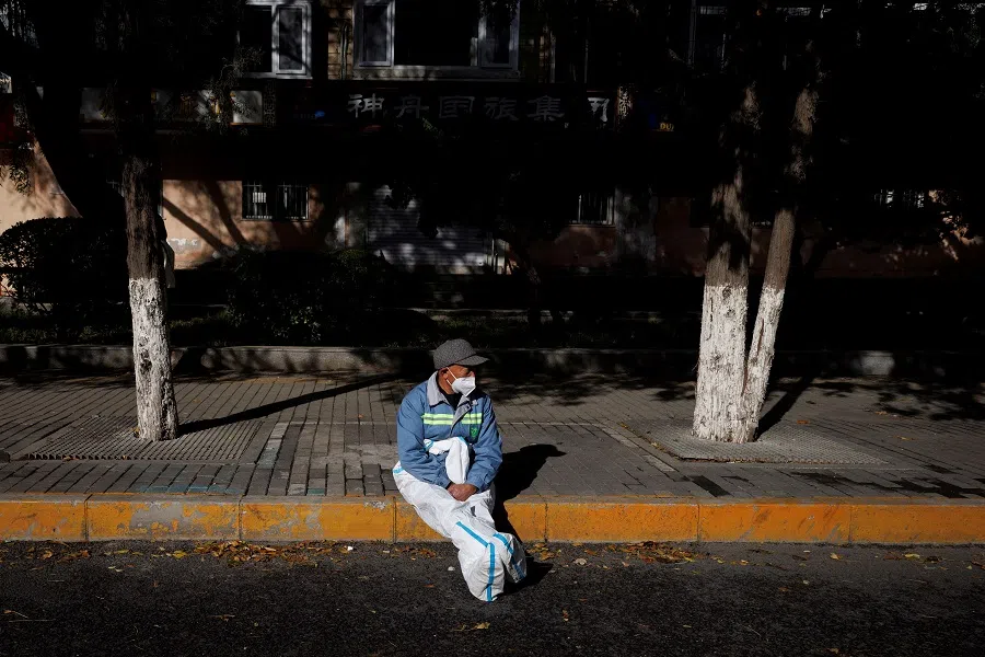 A pandemic prevention worker in a protective suit rests in the sun outside an apartment compound that was placed under lockdown as outbreaks of Covid-19 continue in Beijing, China, 12 November 2022. (Thomas Peter/Reuters)