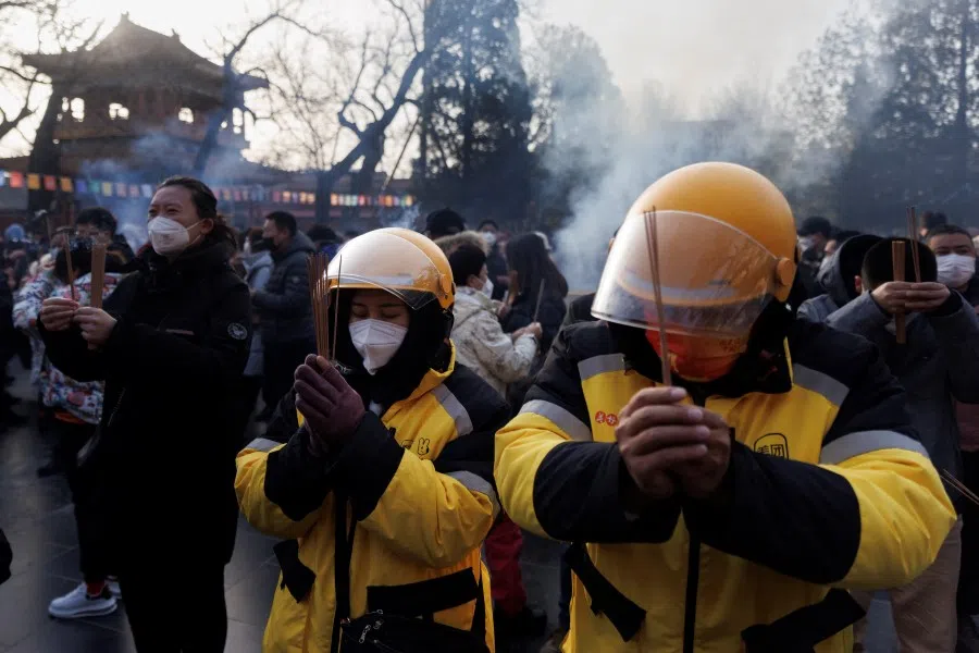 Delivery drivers pray at Lama Temple (Yonghe Temple) on the first day of the Lunar New Year of the Rabbit in Beijing, China, 22 January 2023. (Thomas Peter/Reuters)