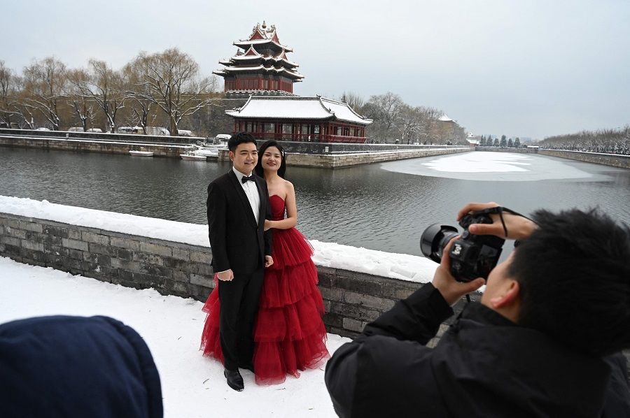 A couple poses for wedding photos in the snow beside the moat which surrounds the Forbidden City, in Beijing, China, on 11 December 2023. (Greg Baker/AFP)