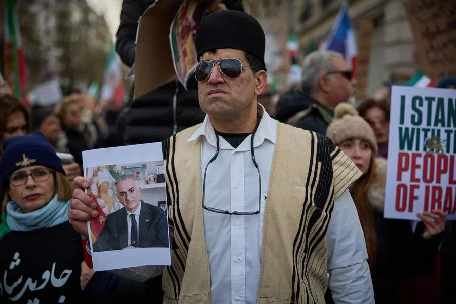 A protestor carries a placard with the image of Iranian opposition leader and son of the last shah of Iran Mohammad Reza Pahlavi during a demonstration to support mass rallies denouncing the Islamic republic in Iran in Paris on 11 January 2026. (Kiran Ridley/AFP)