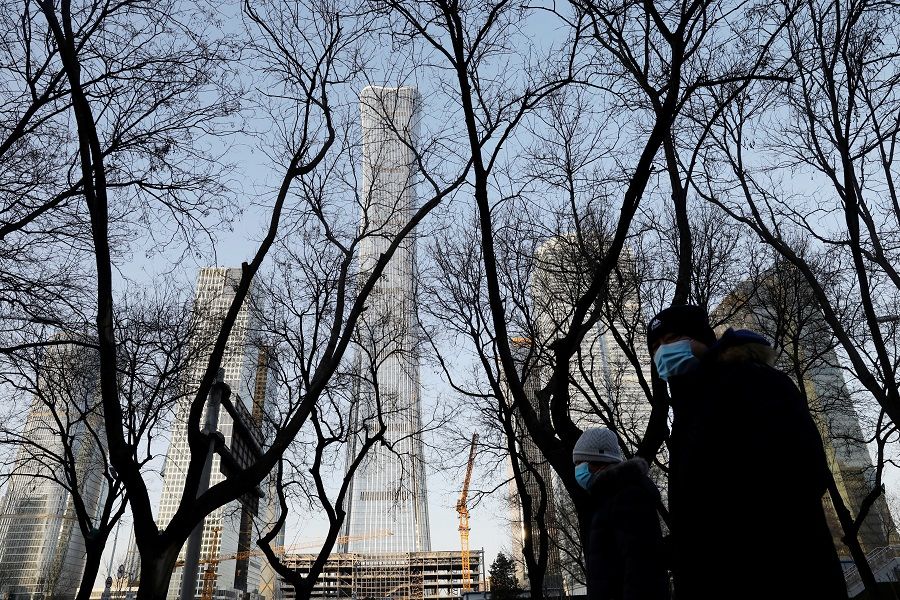 People wearing face masks walk past the China Zun skyscraper at the central business district in Beijing, China, 15 January 2021. (Tingshu Wang/Reuters)