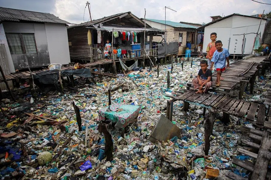 Boys play near rubbish, most of which are plastics, in the coastal settlements of Tanjung Uma, Batam, Riau Islands province, Indonesia, on 15 November 2021.