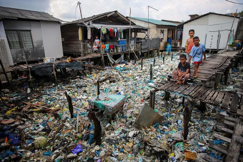 Boys play near rubbish, most of which are plastics, in the coastal settlements of Tanjung Uma, Batam, Riau Islands province, Indonesia, on 15 November 2021. (Teguh Prihatna/Antara Foto via Reuters)