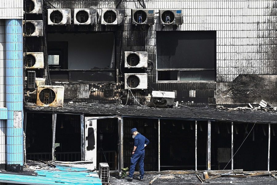 An investigator inspects the damage at the Changfeng Hospital in Beijing, China, on 19 April 2023, after a fire broke out a day earlier. (Greg Baker/AFP)