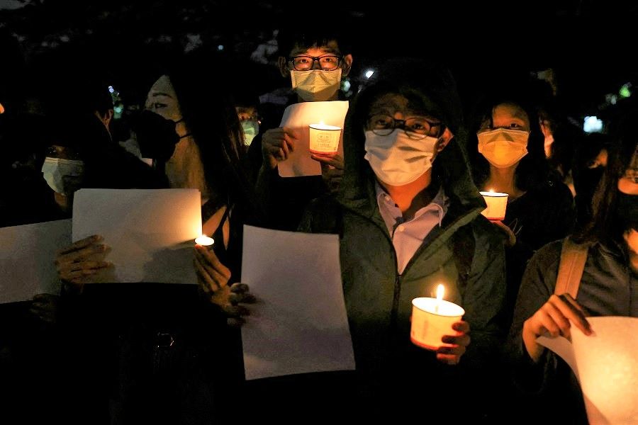 People gather as they hold candles and white sheets of paper to support protests in China regarding Covid-19 restrictions at National Taiwan University in Taipei, Taiwan, 30 November 2022. (Ann Wang/Reuters)