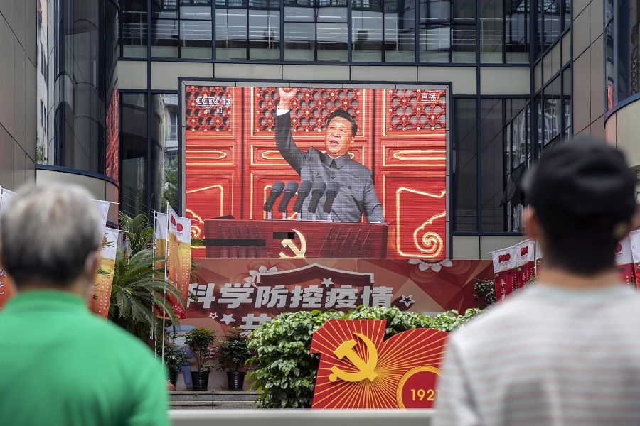Pedestrians watch a screen showing a live broadcast of Chinese President Xi Jinping speaking at a ceremony marking the centenary of the Chinese Community Party taking place at Beijing's Tiananmen Square, in Shanghai, China on 1 July 2021. (Qilai Shen/Bloomberg)