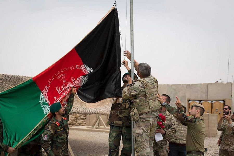 This handout photograph taken on 2 May 2021 and released by Afghanistan's Ministry of Defense shows US soldiers and Afghan National Army soldiers raising Afghanistan's national flag during a handover ceremony to the Afghan National Army army 215 Maiwand corps at Antonik camp in Helmand province, Afghanistan. (Afghanistan Ministry of Defense/AFP)