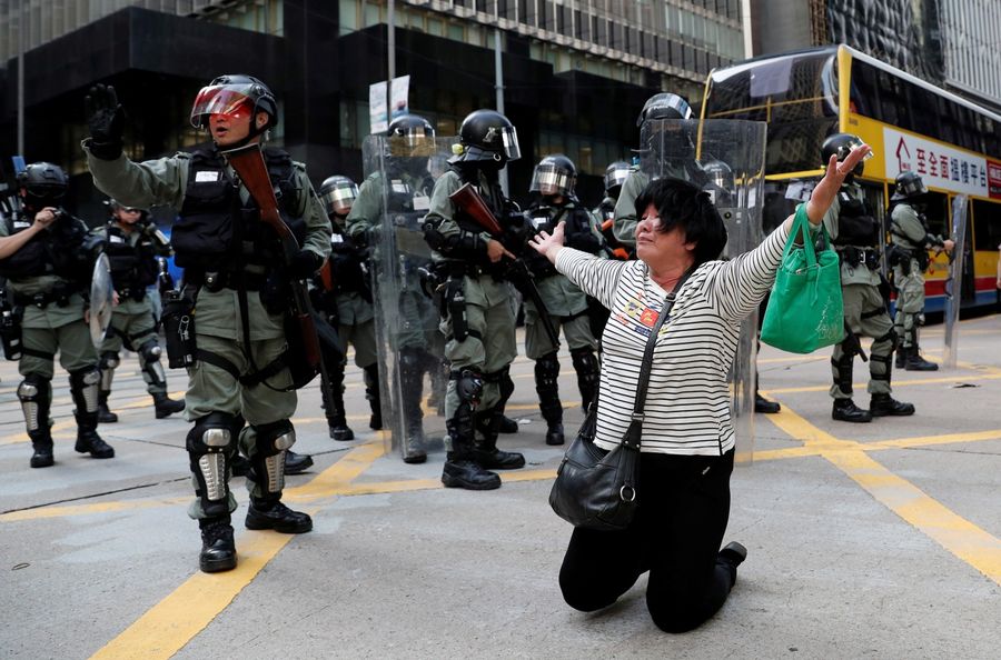 A woman cries and prays in front of riot police during an anti-government protest in Central on November 12, 2019. (REUTERS/Shannon Stapleton)