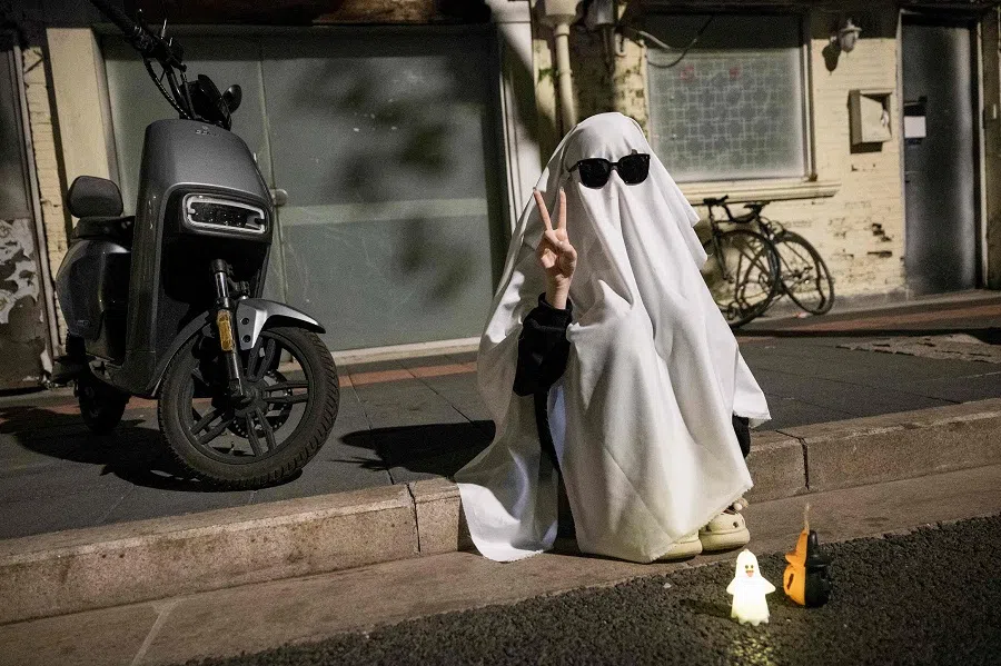 This photo taken on 30 October 2023 shows a person in costume sitting beside the street ahead of Halloween in Shanghai. (AFP)