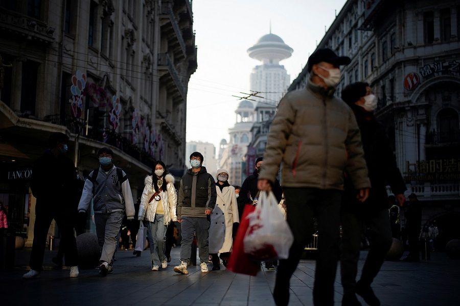 People wearing protective masks walk on a street in Shanghai, China, 30 December 2021. (Aly Song/Reuters)