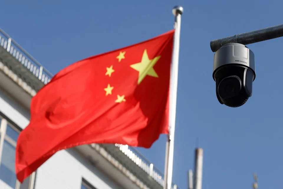 A security surveillance camera overlooking a street is pictured next to a nearby fluttering flag of China in Beijing, China, on 25 November 2021. (Carlos Garcia Rawlins/Reuters)