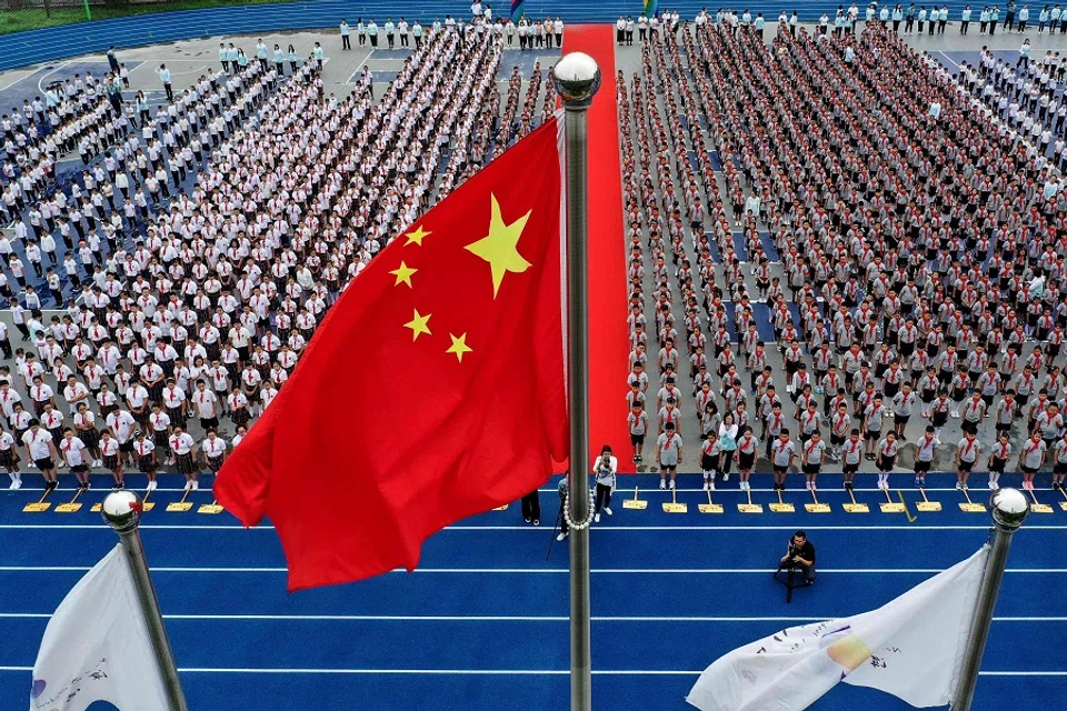 This aerial photo taken on 1 September 2020 shows elementary school students attending a flag-raising ceremony on the first day of the new semester in Shenyang, Liaoning, China. (STR/AFP)