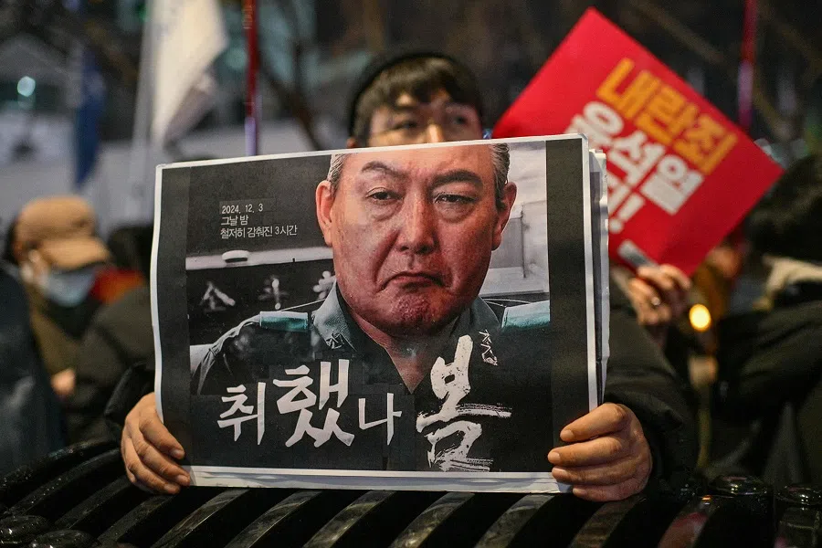 A protester holds a poster with an image of South Korea President Yoon Suk-yeol during a candlelight rally calling for the ouster of the president in Gwanghwamun in Seoul on 5 December 2024.