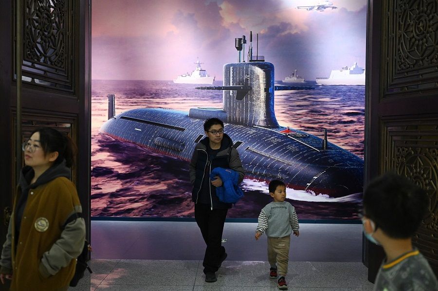 People walk past an illustration of a Chinese nuclear submarine at the Military Museum in Beijing, China, on 3 March 2024. (Greg Baker/AFP)