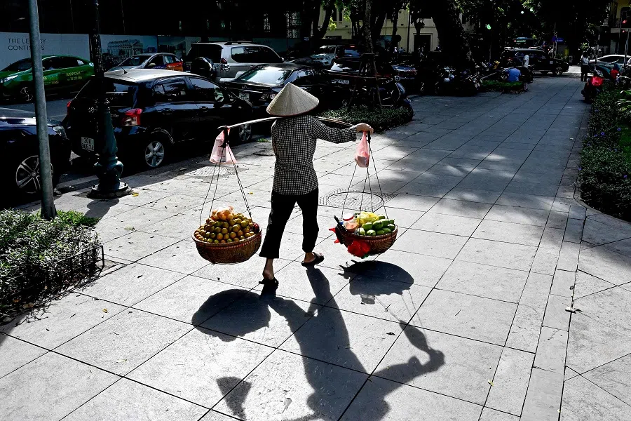A vendor carries fruits for sale along a street in Hanoi on 24 October 2024. (Nhac Nguyen/AFP)