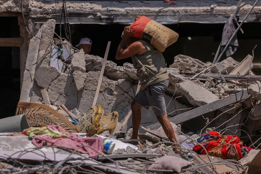 Hassan Hejazieh carries a bag of cement as he walks amid the rubble of a building destroyed in an Israeli airstrike, in Tyre, southern Lebanon, on 5 July 2026.