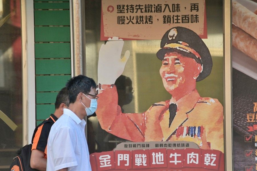 This picture taken on 10 August 2022 shows people walking past an advertisement portrait of the late president Chiang Kai-shek at Kinmen islands. (Sam Yeh/AFP)
