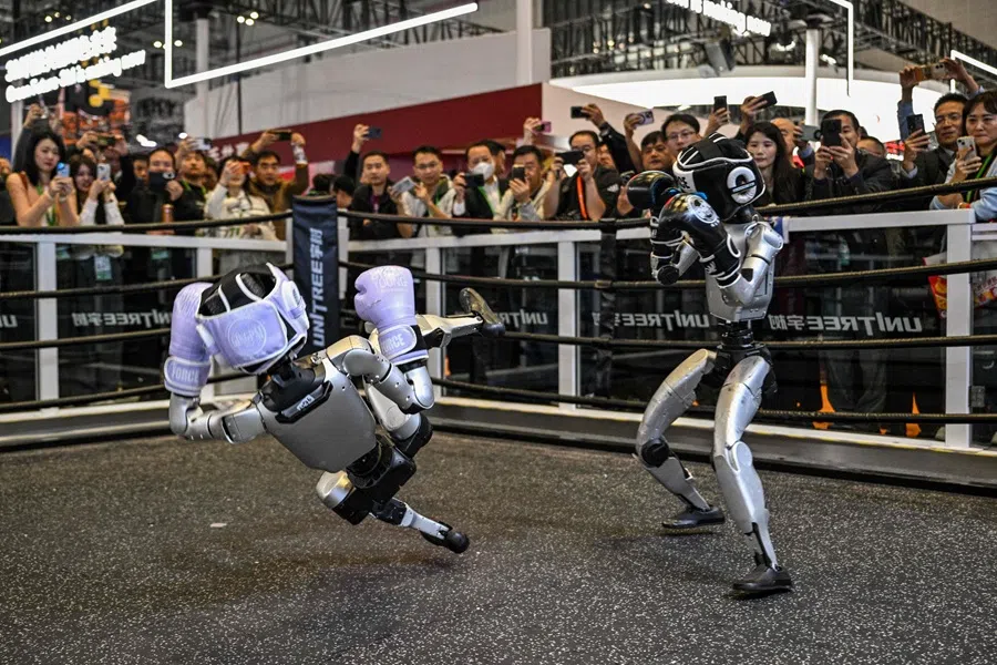 Remote-controlled robots by Unitree Robotics take part in a boxing match at the Unitree Robotics stand during the 8th International Import Expo (CIIE) in Shanghai on 6 November 2025. (Hector Retamal/AFP)