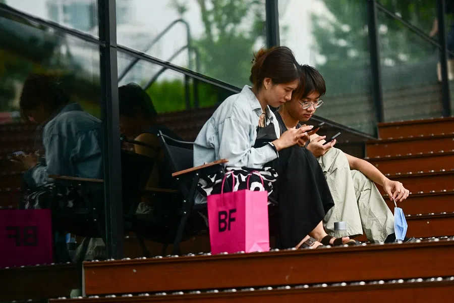 People use their phones outside a shopping centre in Beijing, China, on 17 August 2023. (Pedro Pardo/AFP)