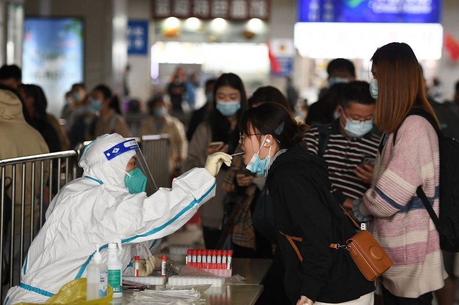 This photo taken on 6 October 2022 shows a passenger undergoing a nucleic acid test for Covid-19 as she arrives at Nanjing Railway Station in Nanjing, Jiangsu province, China. (AFP)