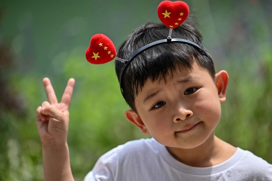 A young boy wearing a head band poses in front of the First National Congress of the Chinese Communist Party in Shanghai, China on 1 July 2021, as the country marks the 100th anniversary of the founding of the party. (Hector Retamal/AFP)