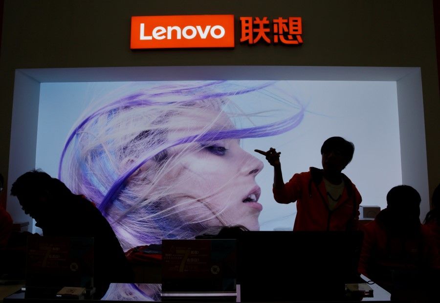 An employee gestures next to a Lenovo logo at Lenovo Tech World in Beijing, China, 15 November 2019. (Jason Lee/Reuters)