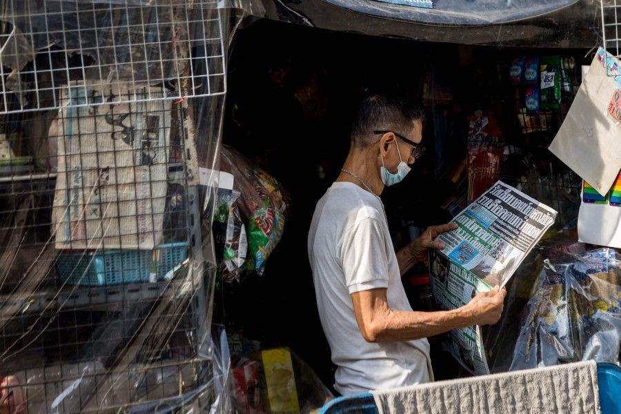 A man reads a Thai newspaper featuring front page coverage of the Russian invasion of Ukraine at his stall in Bangkok on 25 February 2022. (Jack Taylor/AFP)