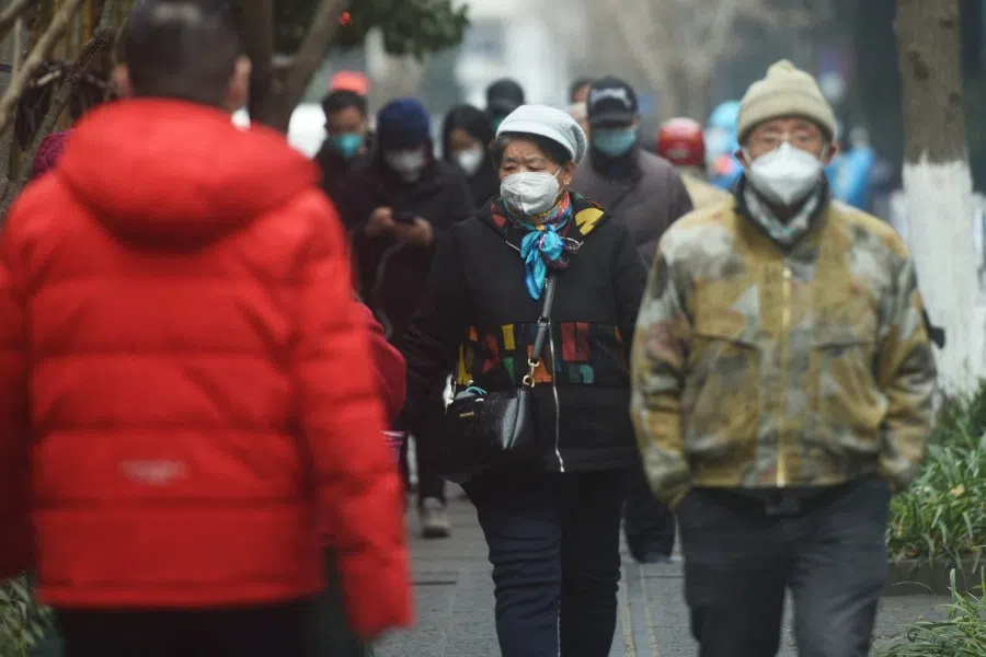 Residents walk along a street in Hangzhou, in China's eastern Zhejiang province on 17 January 2023. (AFP)