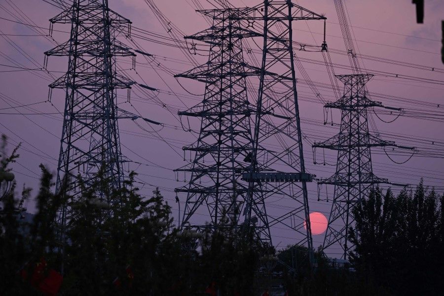 The sun sets behind electricity power pylons in Beijing on 28 September 2021. (Leo Ramirez/AFP)