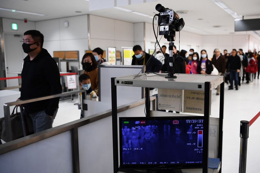Passengers who arrived on one of the last flights from Wuhan walk through a health screening station at Narita airport in Chiba prefecture, outside Tokyo, on 23 January 2020. (Charly Triballeau/AFP)