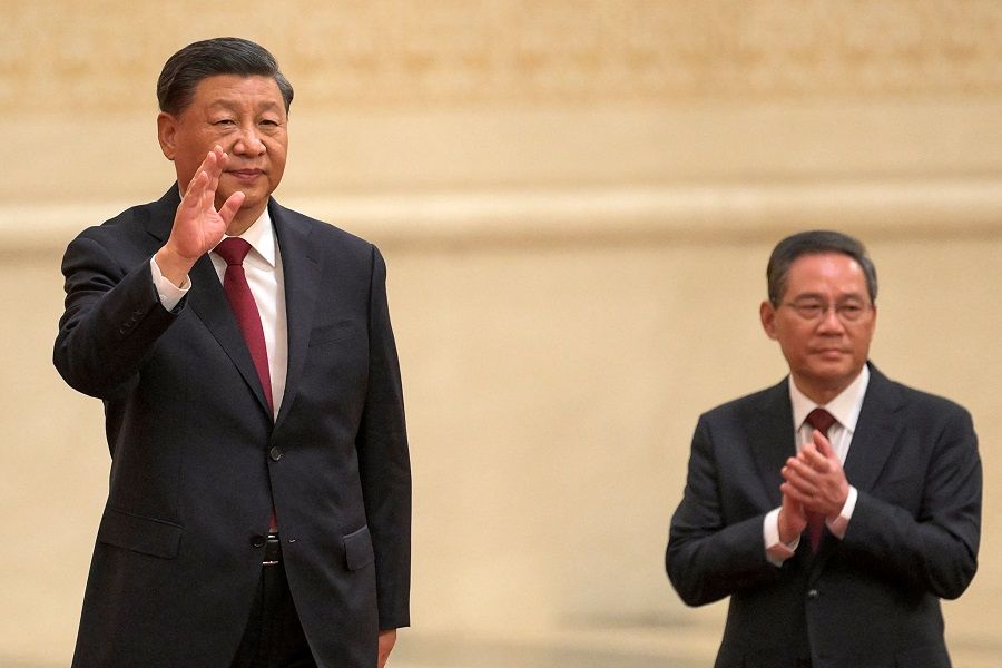 Chinese President Xi Jinping (left) waves with Li Qiang, a member of the Chinese Communist Party's new Politburo Standing Committee, the nation's top decision-making body, as they meet the media in the Great Hall of the People in Beijing, China, on 23 October 2022. (Wang Zhao/AFP)