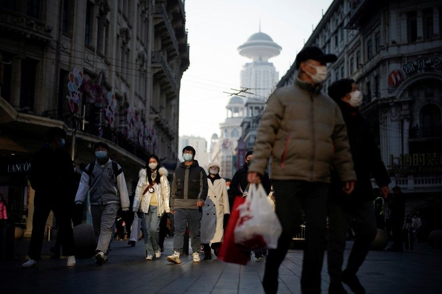 People wearing protective face masks walk on a street, following new cases of the coronavirus disease (Covid-19), in Shanghai, China, 30 December 2021. (Aly Song/Reuters)
