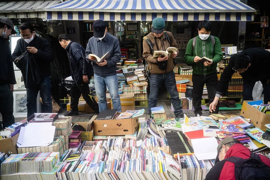 Customers browse through a display of used books for sale at the Dongmyo Flea Market in Seoul on 15 April 2025. (Anthony Wallace/AFP)