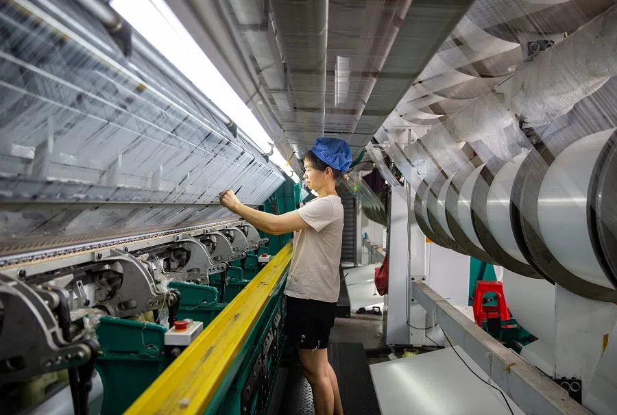 A worker checks equipment at a textile factory in Haian city in China's eastern Jiangsu province, on 16 August 2023. (AFP)