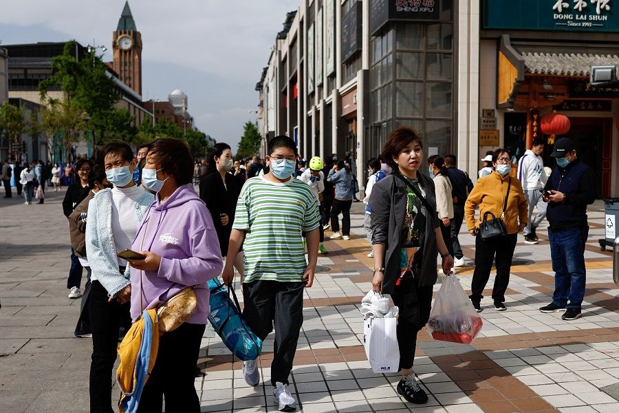 People walk at a shopping street in Beijing, China, 15 April 2023. (Tingshu Wang/Reuters)