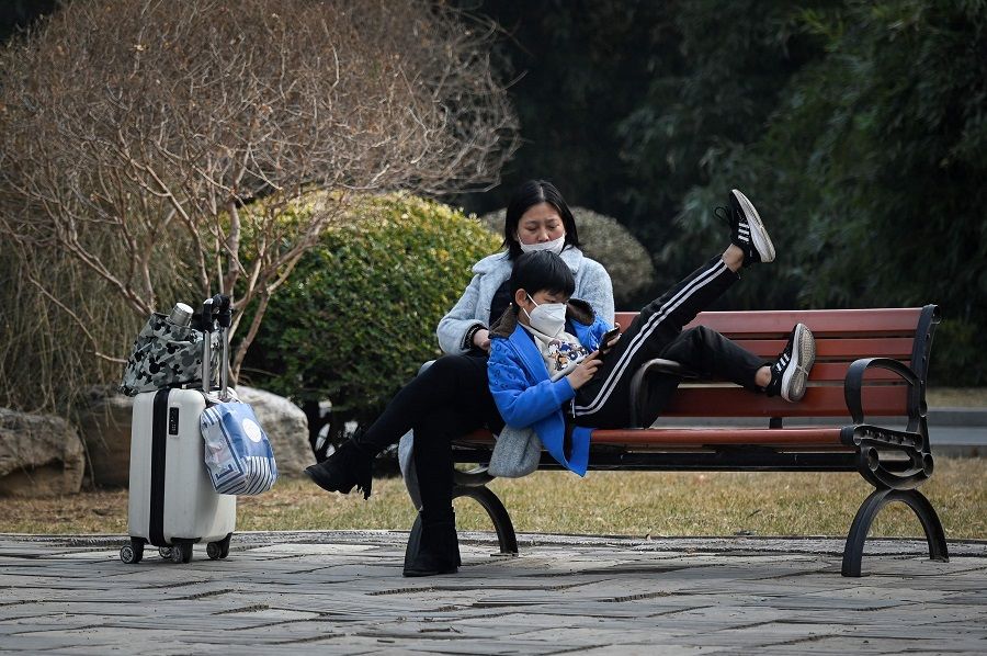 A boy and a woman rest on a bench at a park in Beijing, China, on 27 February 2023. (Wang Zhao/AFP)