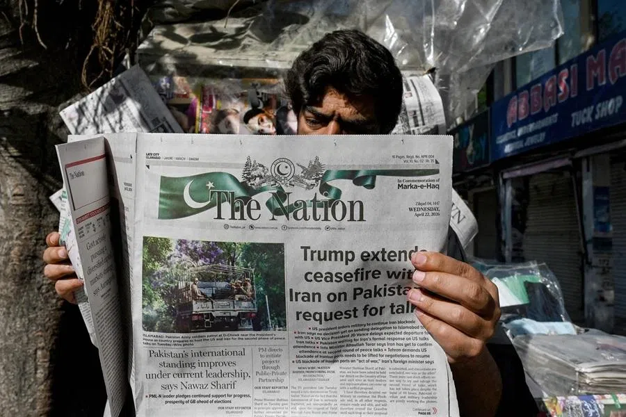 A man reads a newspaper with a front page article referring to anticipated US-Iran peace talks, at a stall in Islamabad on 22 April 2026.