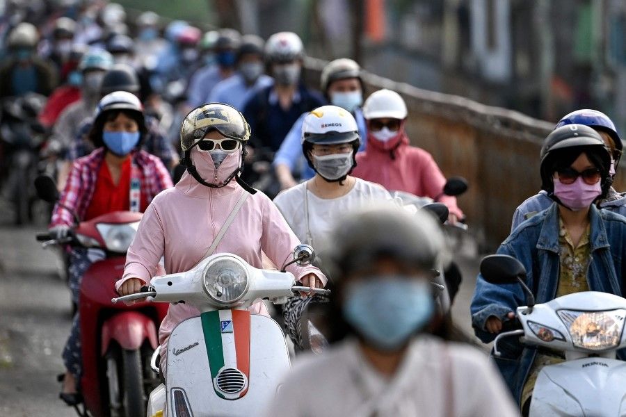 Morning commuters wearing face masks ride past in Hanoi on 4 May 2021. (Manan Vatsyayana/ AFP)