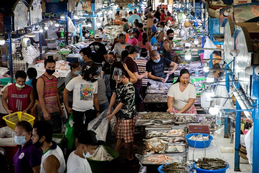 Vendors and customers wearing face masks are seen inside a public market in Quezon City, Metro Manila, the Philippines, 5 February 2021. (Eloisa Lopez/Reuters)