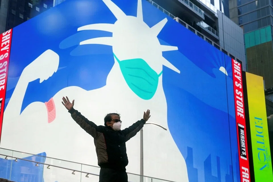 A man poses for a photo on the Red Steps in Times Square as an image of the Statue of Liberty wearing a mask is projected on a billboard amid the Covid-19 pandemic in the Manhattan borough of New York City, New York, US on 20 April 2021. (Carlo Allegri/Reuters)