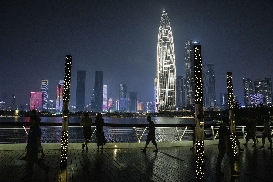 Pedestrians pass in front of the KK100 skyscraper while walking through a park at night in Shenzhen, China, on 30 September 2021. (Gilles Sabrie/Bloomberg)