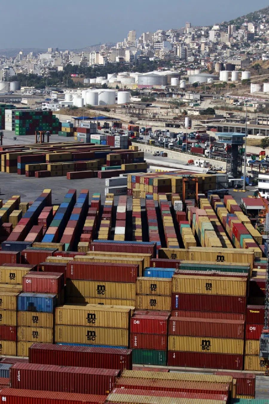Shipping containers stand on the dockside as storage tanks and residential and commercial property stand beyond, at the commercial terminal of Piraeus Port, operated by Piraeus Port Authority SA, in Athens, Greece, on 14 October 2013. (Kostas Tsironis/Bloomberg)