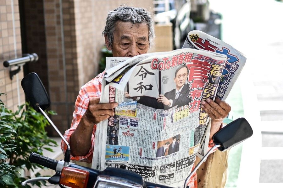 A man reads a newspaper on a street in Tokyo, 29 August 2020. (Charly Triballeau/AFP)
