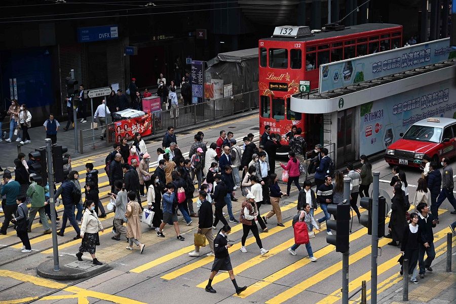 People cross an intersection in the central business district of Hong Kong on 27 February 2024. (Peter Parks/AFP)