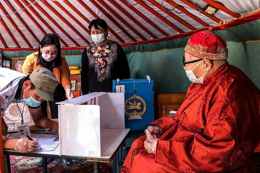 An elderly resident (right) who cannot go out to vote watches staff members as they prepare a ballot box and ticket for him to vote at his home in Ulaanbaatar on 23 June 2020. (Byambasuren Byamba-ochir/AFP)
