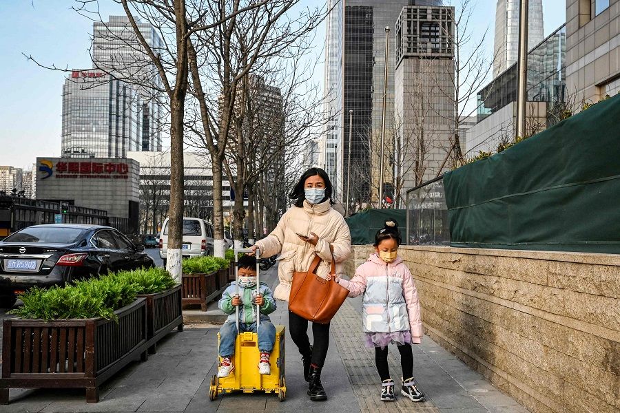 A woman walks along a street with two children in Beijing, China, on 3 February 2023. (Jade Gao/AFP)