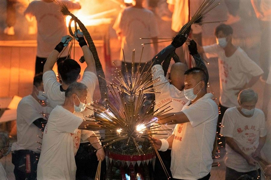 Performers place the joss sticks on the "fire dragon" during the Tai Hang Fire Dragon dance at Tai Kwun in Hong Kong, China, on 20 November 2022. (Bertha Wang/AFP)